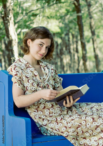 Photo: Pretty young woman/girl reading a book outdoors Pretty young woman/girl reading a book outdoors