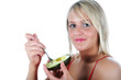 Pretty blonde girl holding and eating a avocado