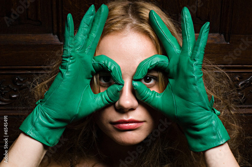 Woman looking through fingers in green gloves