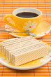Waffle slice and cup with coffee on bamboo table-cloth