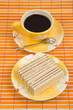 Waffle slice and cup with coffee on bamboo table-cloth