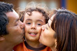 parents kissing their son