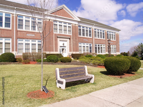 Photo: park bench in front of a red brick building park bench in front of a red brick building