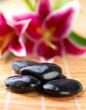 Spa stones on mat with flower in background Spa stones on mat with flower in background