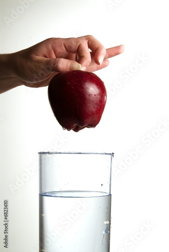 Photo: A hand dropping an apple in glass water A hand dropping an apple in glass water