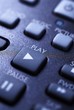 A closeup of a remote control focusing on the play button.