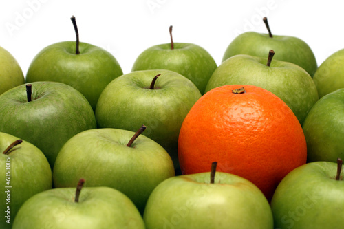 Photo: different concepts - orange between apples different concepts - orange between apples