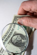 Male hand with one dollar bill and magnifying glass