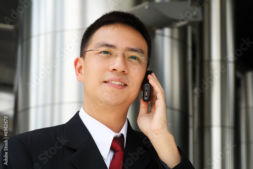 Photo: Young asian executive talking on handphone Young asian executive talking on handphone