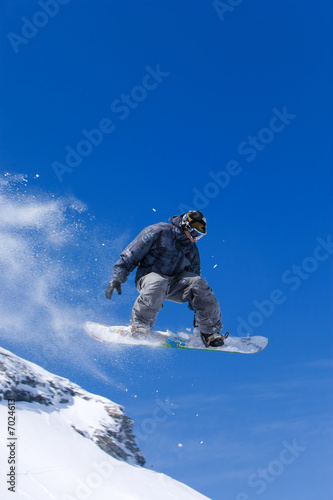 Foto: Male snowboarder jumping of a hill Male snowboarder jumping of a hill