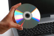 Close up. Woman with cd disk in a hand used notebook