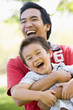 Foto: Asian father and son having fun in park Asian father and son having fun in park