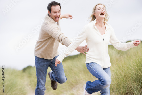 Photo: Couple chasing one another through dunes Couple chasing one another through dunes