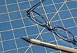 Stainless steel razor knife and glasses on a blue cutting mat Stainless steel razor knife and glasses on a blue cutting mat