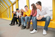 group of young persons sit on footbridge