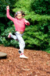 Young girl having fun leaping high from a wooden board,