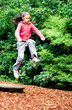 Little girl leaps in the air, jumping off a wooden board 