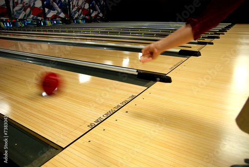 Photo: a human hand bowling a ball down a lane. a human hand bowling a ball down a lane.