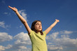 Girl holding hands up against blue sky
