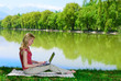 Beautiful young woman with laptop near the lake