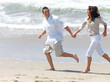 Young couple on beach, running hand in hand.