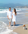 Young couple walking on beach with dog