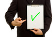 Green tick on clipboard in the hand of a businessman
