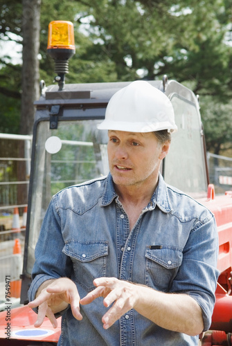 Photo: A consruction worker explaining to his collegue. A consruction worker explaining to his collegue.