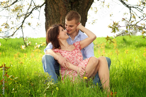 Photo: young and happy couple is cuddle on a meadow young and happy couple is cuddle on a meadow