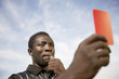 Soccer referee holding out red card and blowing whistle, portrait