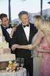 Middle-aged couple with young man and woman gathered near wedding cake