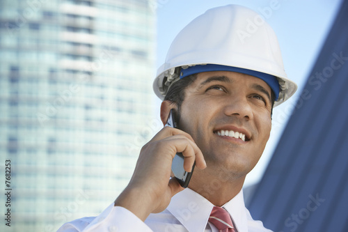 Foto: Businessman in hardhat using mobile phone outdoors Businessman in hardhat using mobile phone outdoors