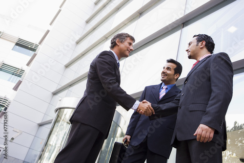 Group of businessmen shaking hands outside office