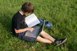 Photo: Student on campus with books and laptop. Student on campus with books and laptop.