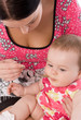 Foto: Young woman feeding her baby daughter Young woman feeding her baby daughter