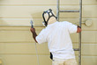 A man on a ladder uses paint spray gun A man on a ladder uses paint spray gun