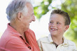 Grandfather and grandson smiling outdoors.