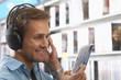 Photo: Young man wearing headphones, listening to CDs in record shop, smiling, close-up, side view Young man wearing headphones, listening to CDs in record shop, smiling, close-up, side view