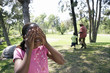 Photo: Grandfather playing hide and seek with two grandchildren (5-10) in park, girl covering eyes Grandfather playing hide and seek with two grandchildren (5-10) in park, girl covering eyes
