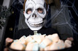 Boy in a skeleton costume at a Hallowe'en party, holding a tray of sweets