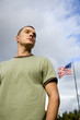 A young man standing by an American flag