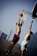 Foto: Two Young African American man jumping with a basketball on an urban basketball court Two Young African American man jumping with a basketball on an urban basketball court