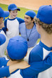 Little league baseball team in huddle with their coach