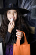 Girl in a witch's costume at a Hallowe'en parting, eating sweets