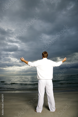 Photo: A man standing on a stormy beach A man standing on a stormy beach