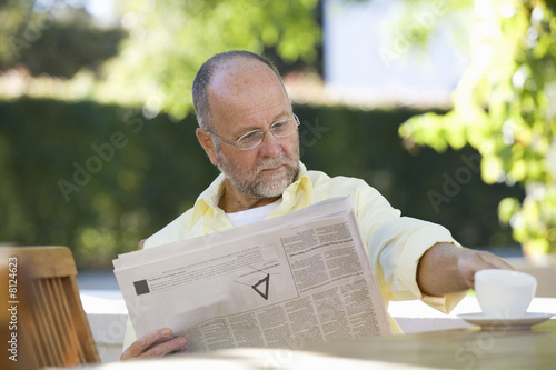Foto: A senior man reading the paper in the garden A senior man reading the paper in the garden