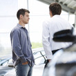 A young man talking to a car salesman