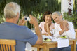 Foto: A group of senior couples at a restaurant, man taking picture with digital camera A group of senior couples at a restaurant, man taking picture with digital camera