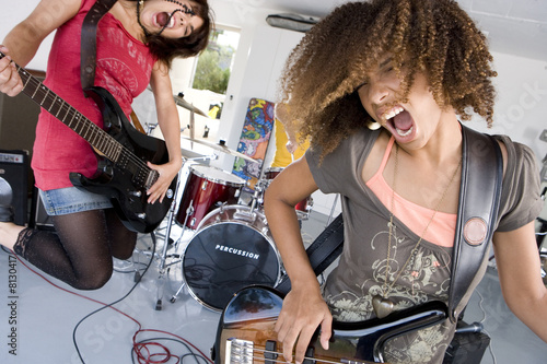 Photo: Three teenage girls (15-17) in garage band, teenage girl playing electric guitar in foreground Three teenage girls (15-17) in garage band, teenage girl playing electric guitar in foreground