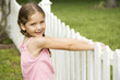 little girl standing by picket fence